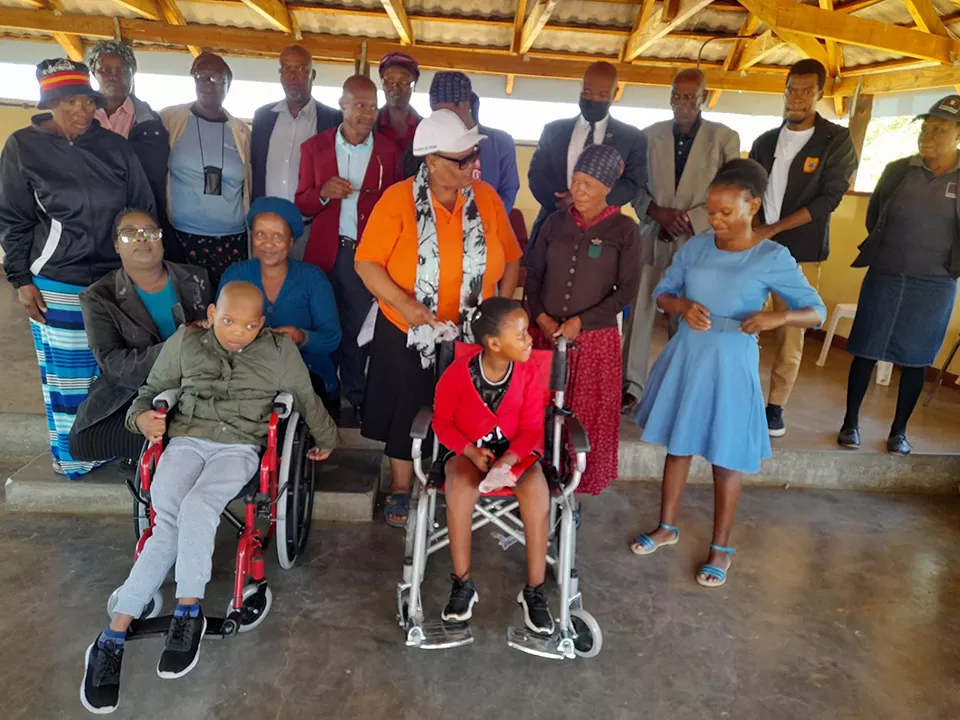 Adults around children in donated wheelchairs